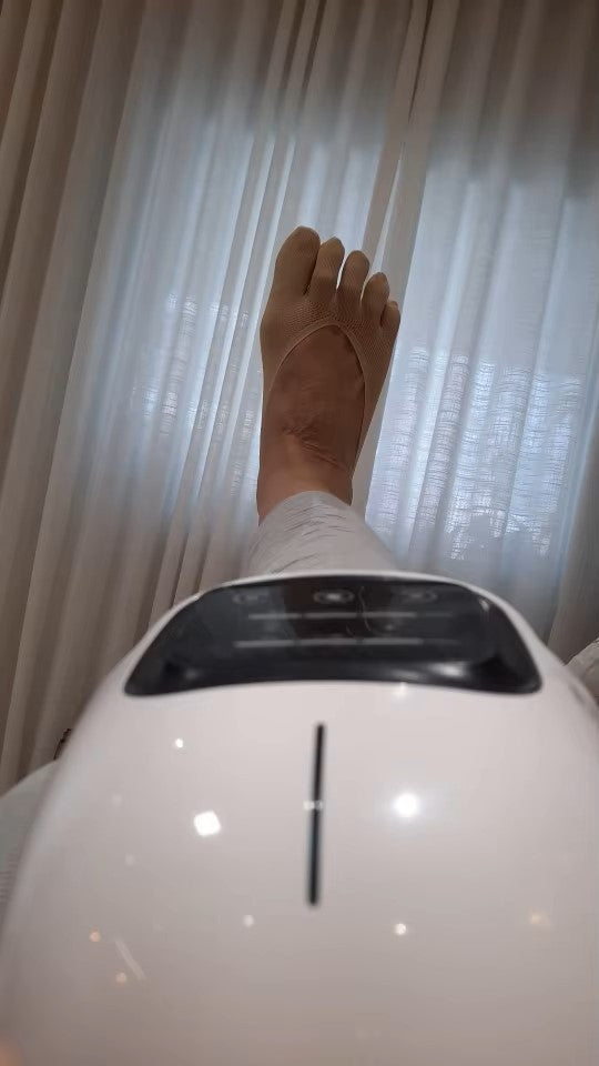 Customer using a knee massager while resting, highlighting the compact design and relaxation benefits during recovery or leisure time